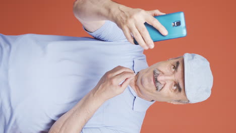 Vertical-video-of-Old-man-making-a-video-call-on-the-phone.